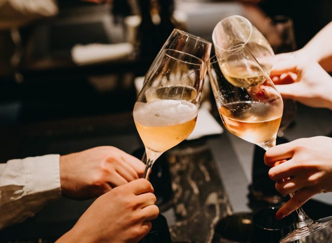 Closeup of people with glasses of champagne at a restaurant.