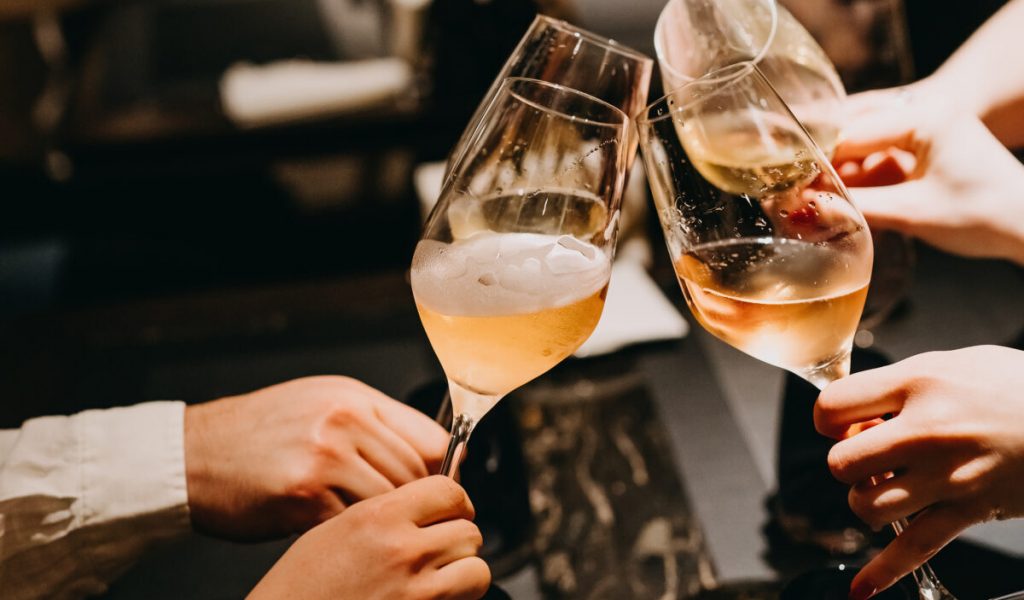 Closeup of people with glasses of champagne at a restaurant.